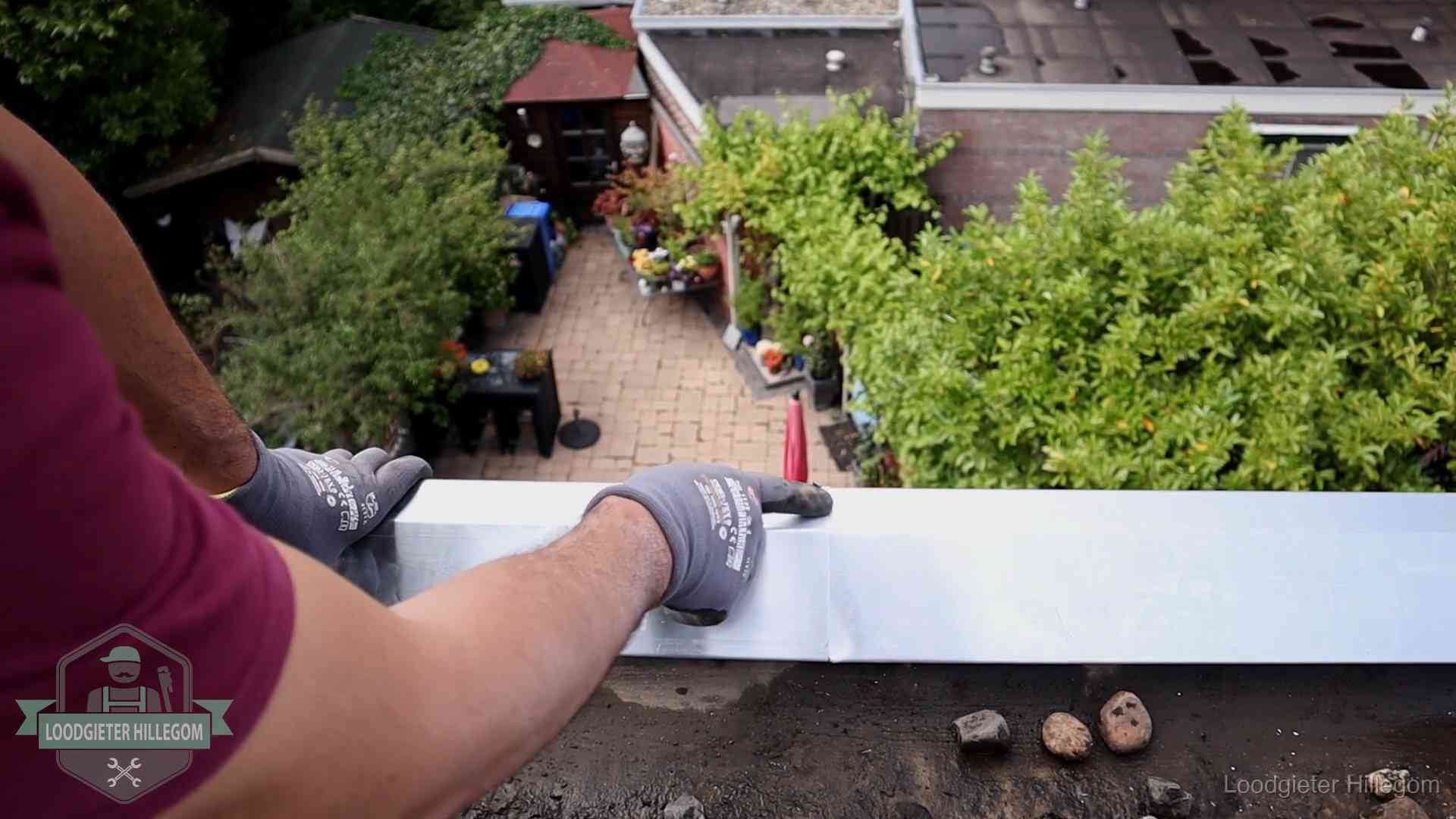 Vakman plaatst een daktrim op de dakrand van een woning in Hillegom