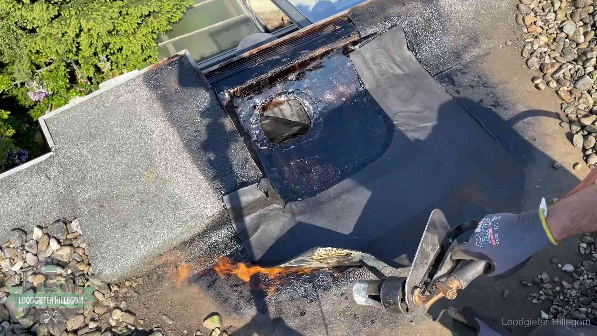 Dakdekker brandt bitumen rond een doorvoer tijdens een daklekkage-reparatie in Hillegom