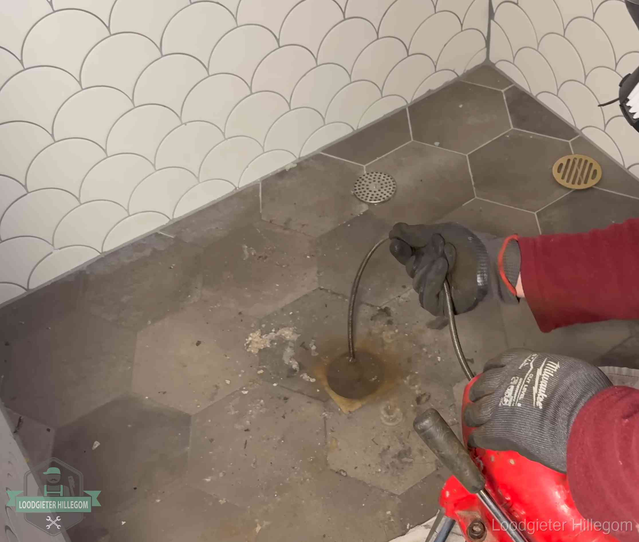 Ontstoppingsveer gaat in een geopend doucheputje in Hillegom waar het water omhoogkwam