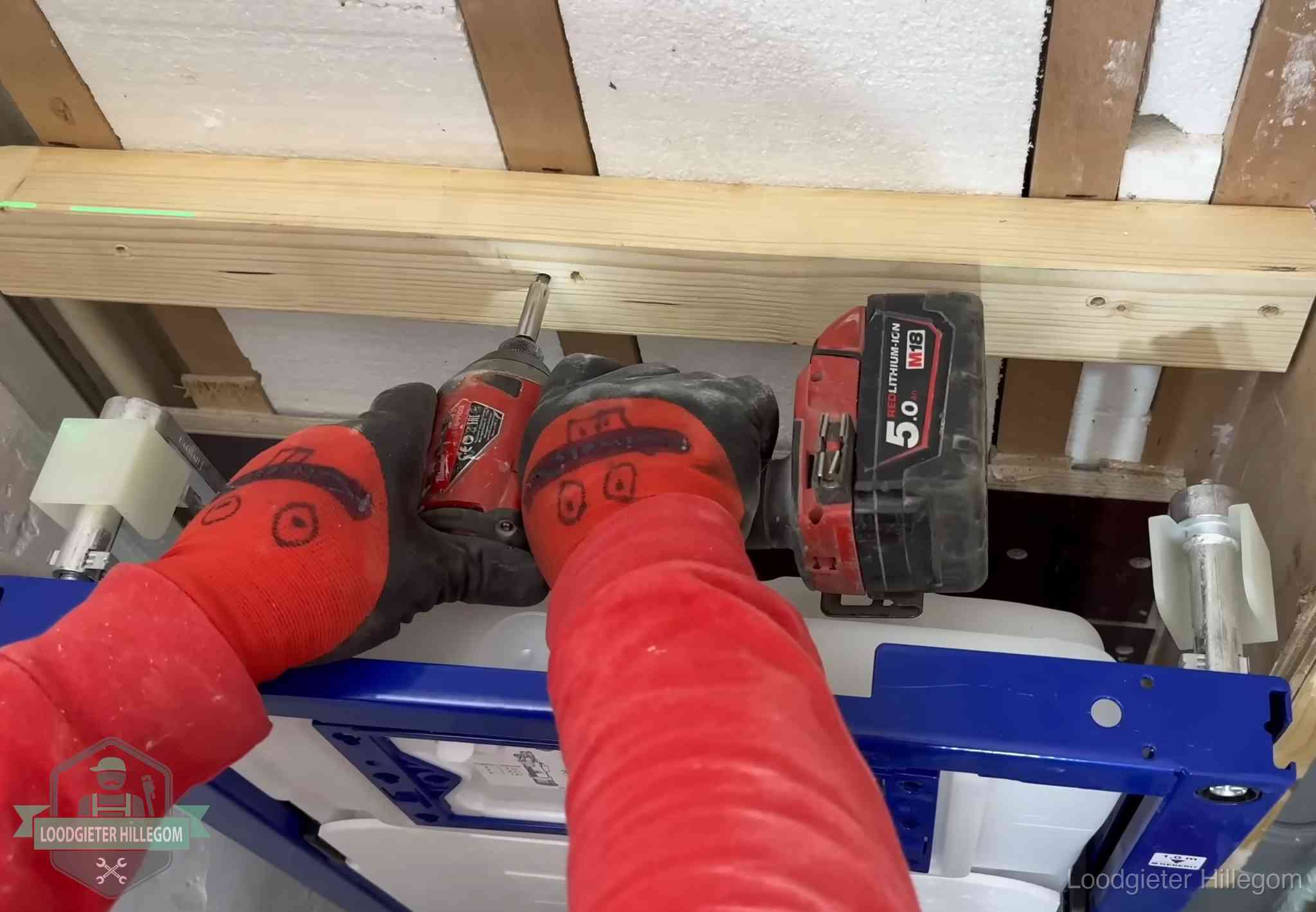 Monteur bevestigt een inbouwreservoir voor een hangend toilet in Hillegom
