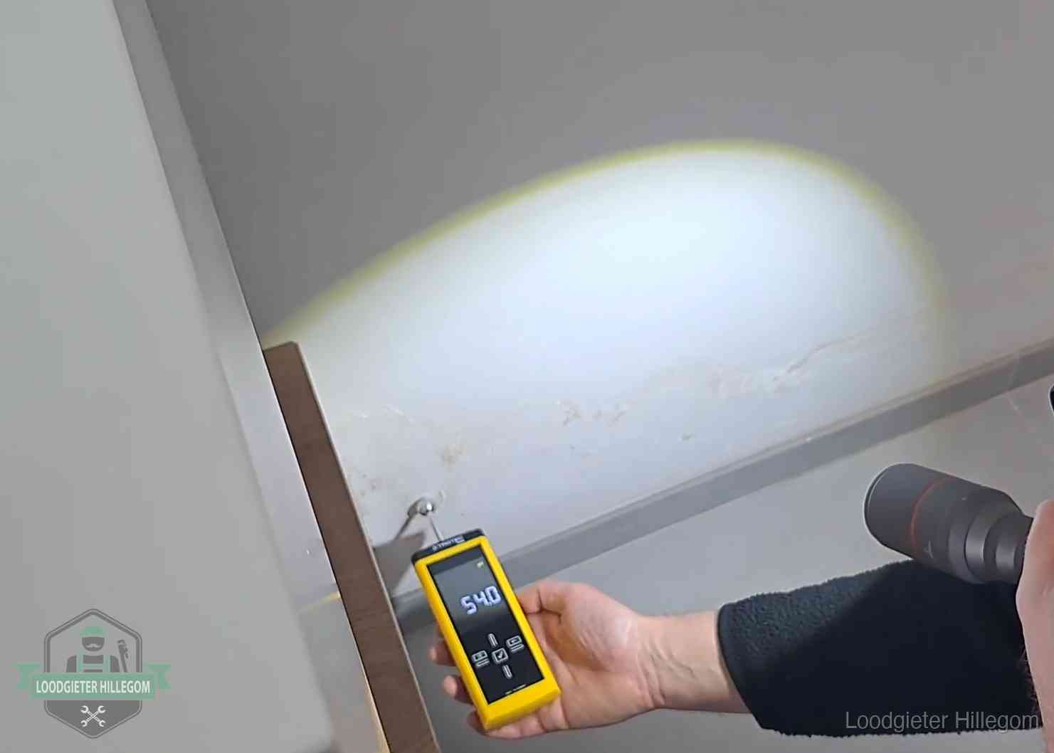 Vochtmeter tegen een natte wand met lekkagesporen in Hillegom