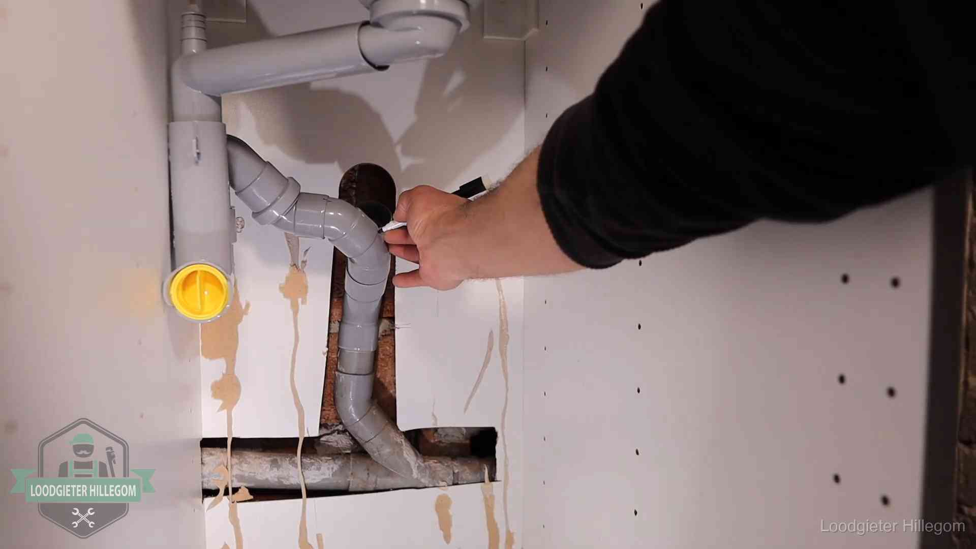 Loodgieter markeert een pvc-afvoerbuis onder een gootsteen in Hillegom