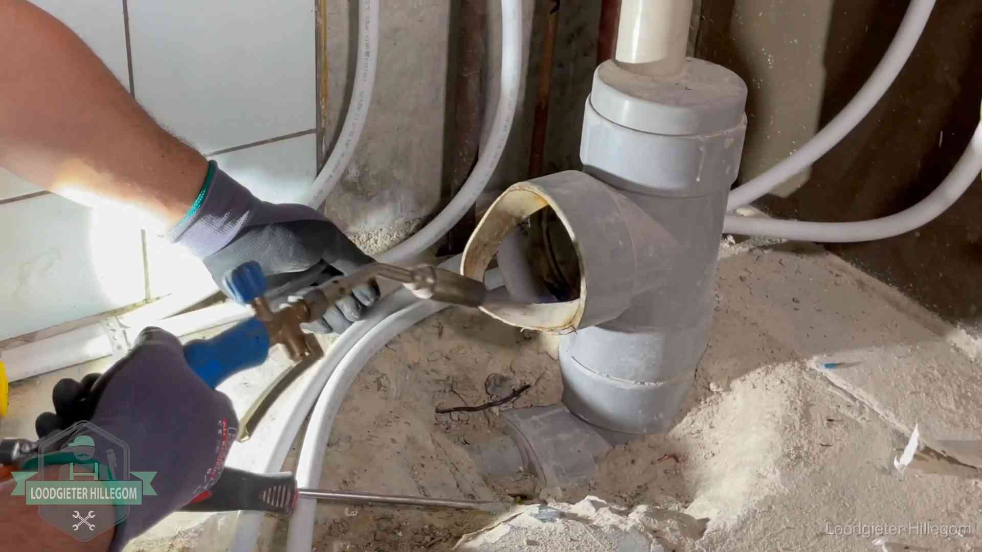 Loodgieter werkt met brander en messing kraanwerk aan leidingen in Hillegom