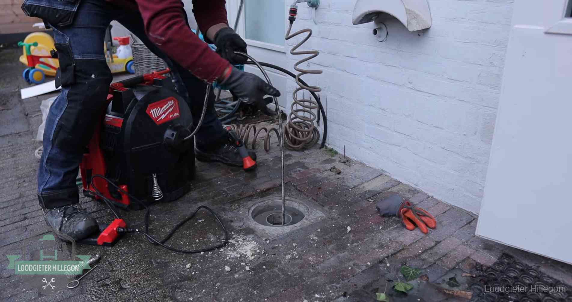 Ontstoppingsputje in de bestrating naast de gevel van een woning in Hillegom
