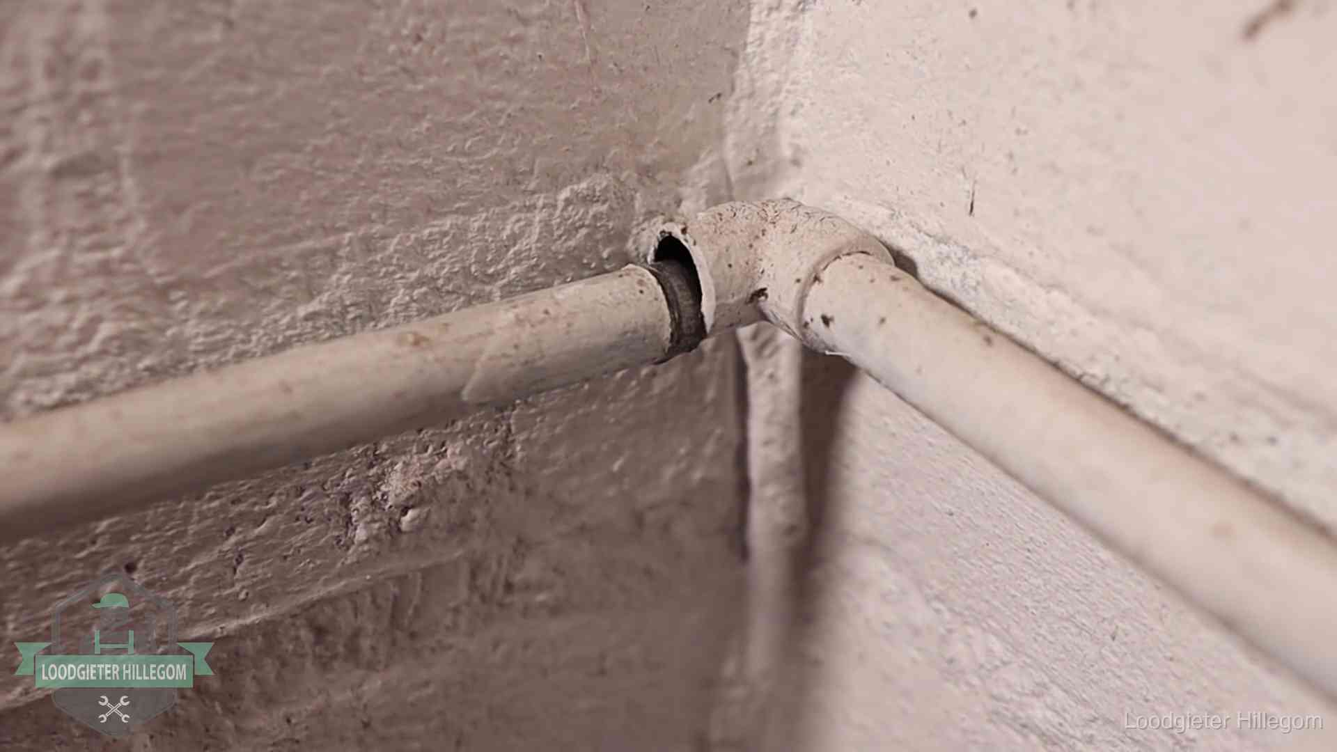 Oude geverfde waterleiding met een losliggende fitting in een woning in Hillegom