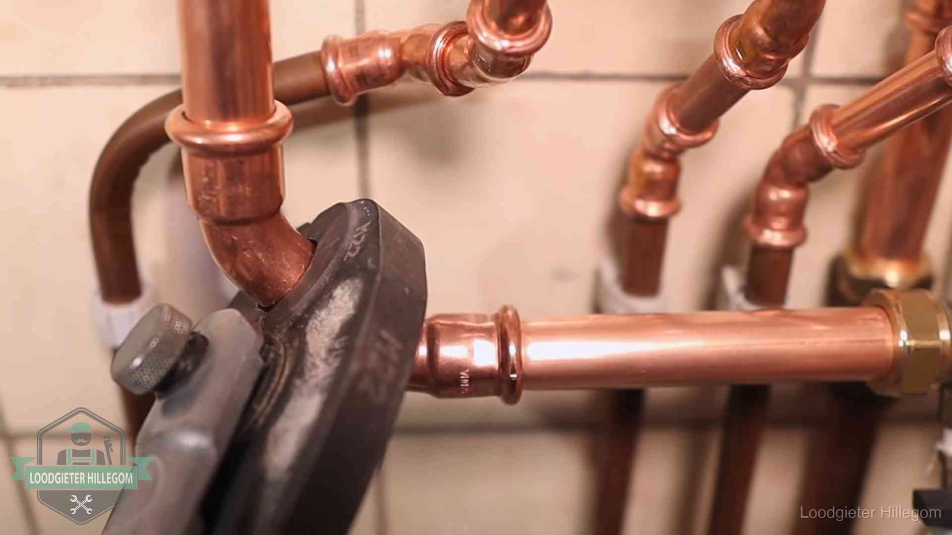 Persmachine perst een koperen fitting op nieuw leidingwerk in Hillegom