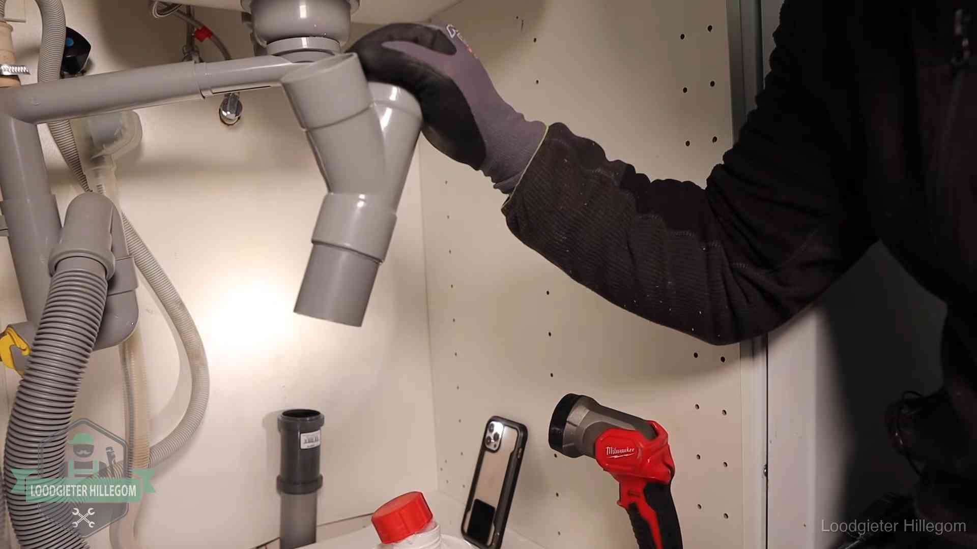 Loodgieter demonteert het sifon- en afvoerwerk onder een gootsteen in Hillegom bij stankklachten