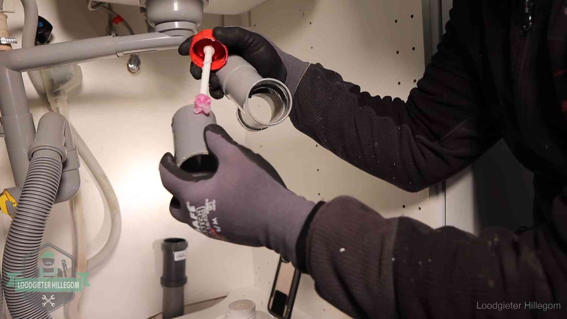 Loodgieter demonteert en reinigt de sifon onder een keukenkast in Hillegom